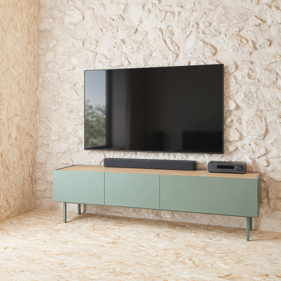 Green console table against a stone wall in a room with wooden floor and ceiling.