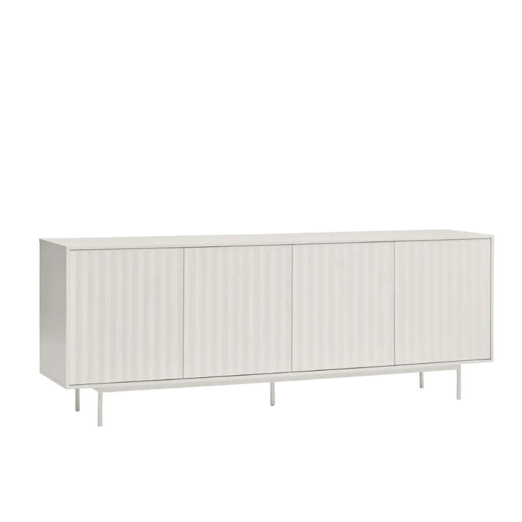 A long, low sideboard cabinet with four vertically ribbed doors, shown in a light warm gray or off-white finish on a clean white background.