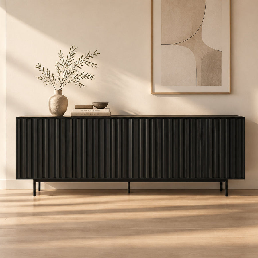 A modern black sideboard or credenza with a fluted front panel and slim black legs, shown against a plain white background.