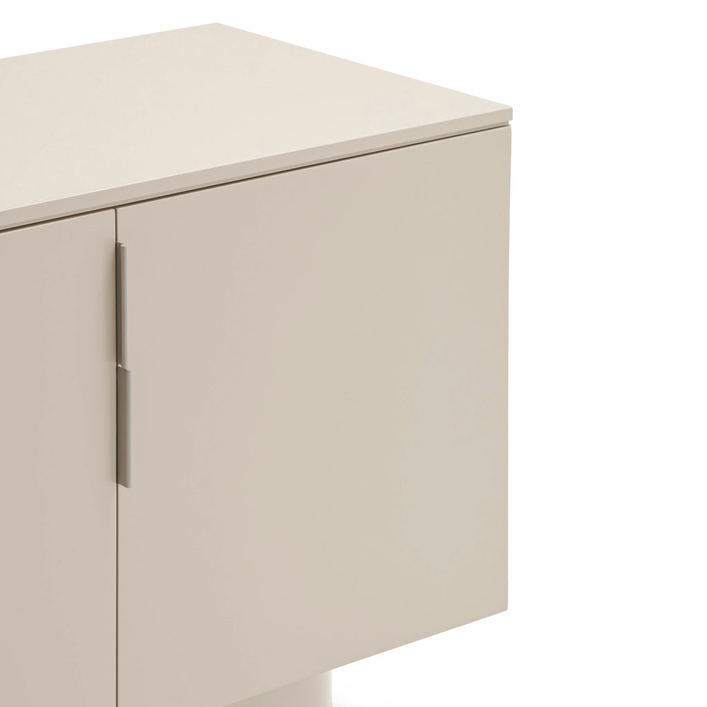 Close-up of a modern sideboard cabinet with a warm beige finish, featuring a curved base and slim vertical metal handles on a white background.