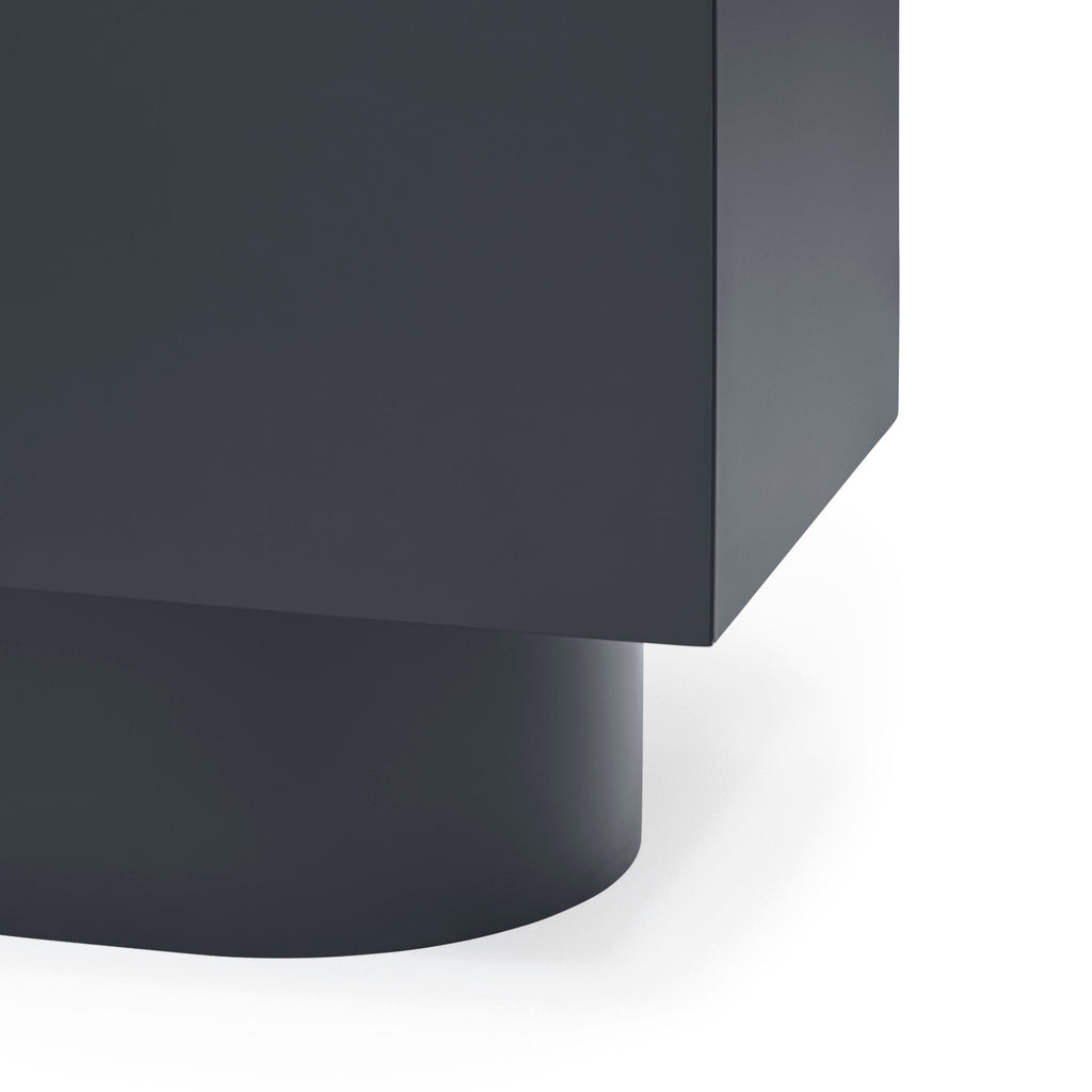 Close-up of a matte black modern furniture piece showing a cylindrical base and a rectangular upper section on a white background.