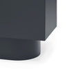 Close-up of a matte black modern furniture piece showing a cylindrical base and a rectangular upper section on a white background.
