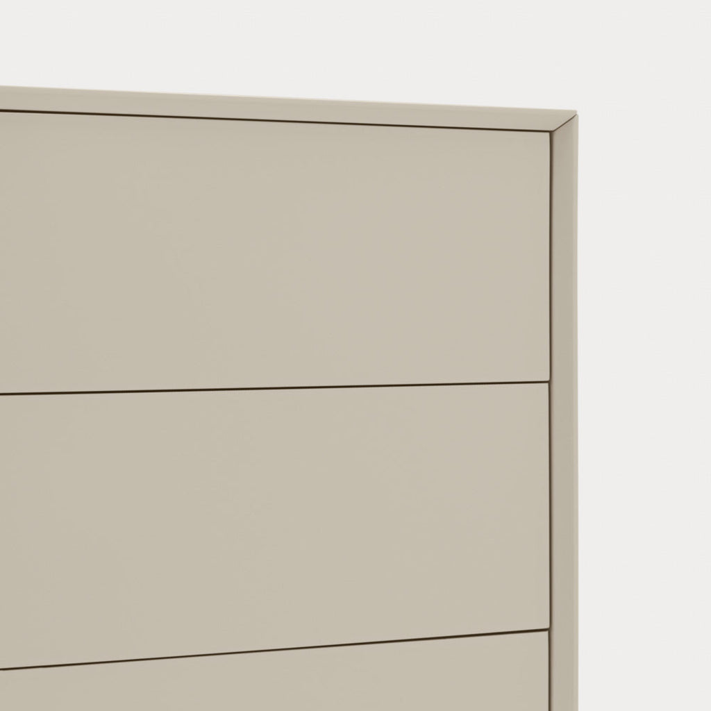 Close-up of a light beige or warm gray dresser drawer front with thin dark line accents and a subtle shadow, set against a very light neutral background.