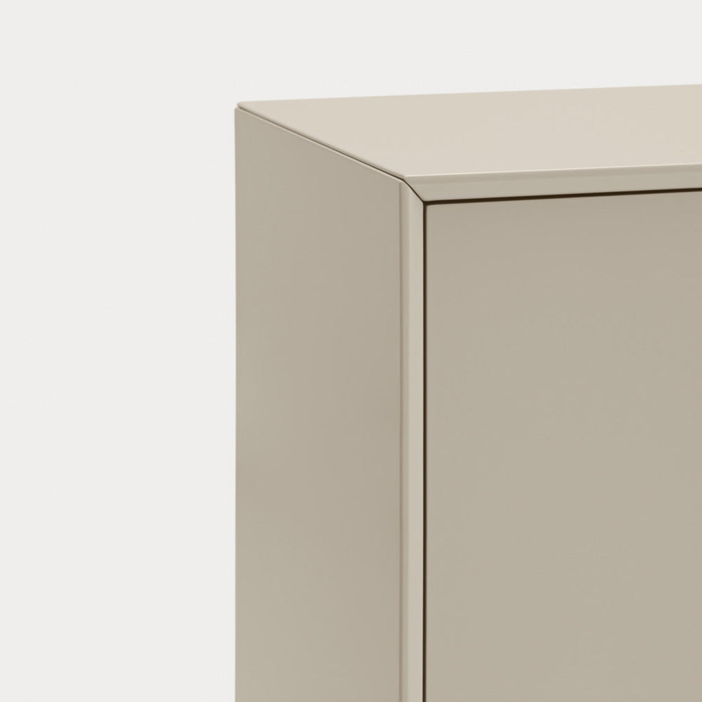 Close-up of a minimalist cabinet corner with a smooth, matte beige finish against a clean white background.