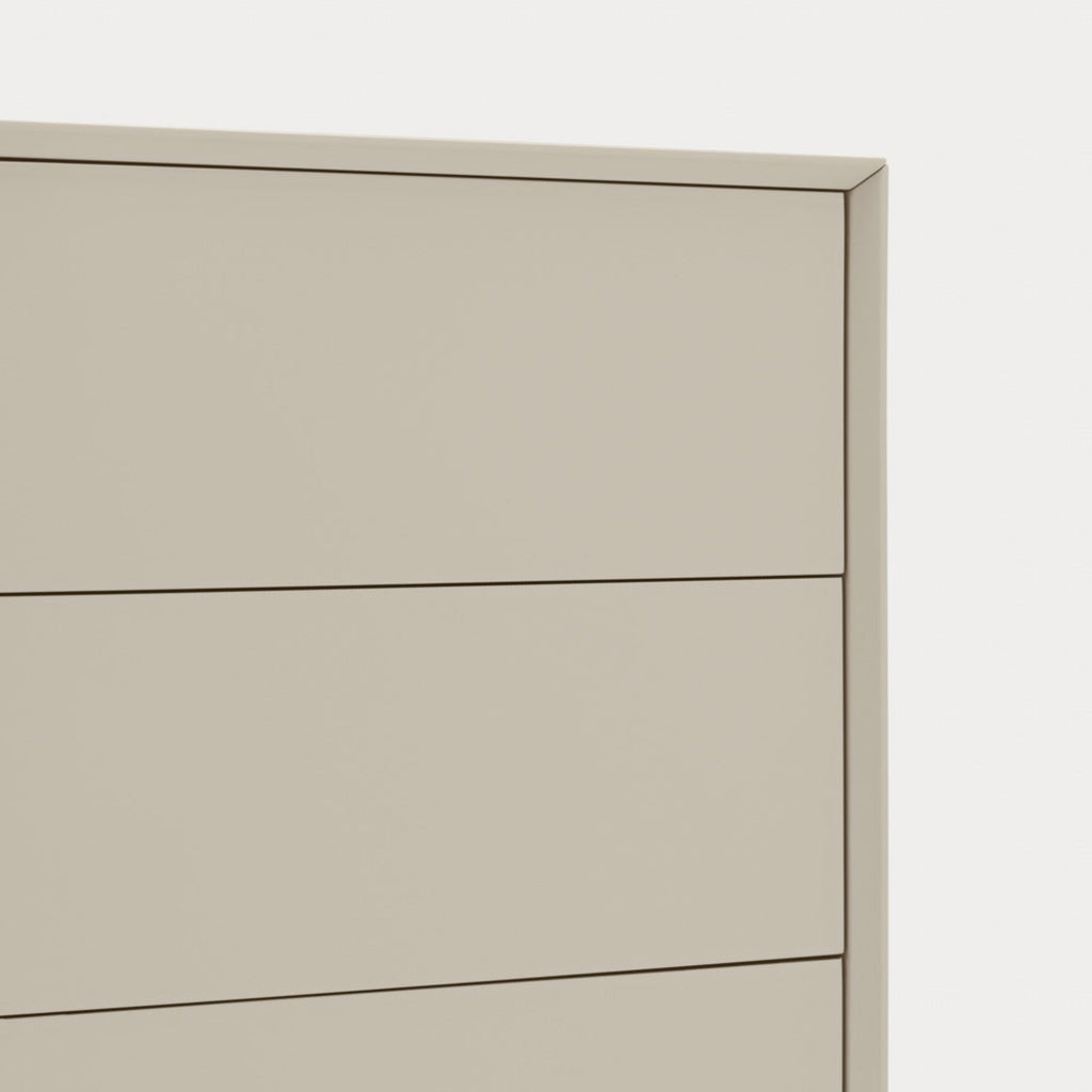 Close-up of a light beige or warm gray dresser drawer front with thin dark line accents and a subtle shadow, set against a very light neutral background.