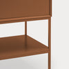 Close-up of a modern cabinet or side table with a warm brown finish, showing the front of a drawer, open shelf, and slim legs against a light gray background.
