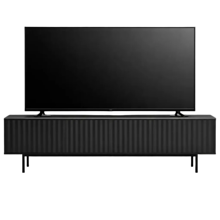 A modern black TV stand with a ribbed front and slim legs, supporting a large black flat-screen television, shown against a plain white background.